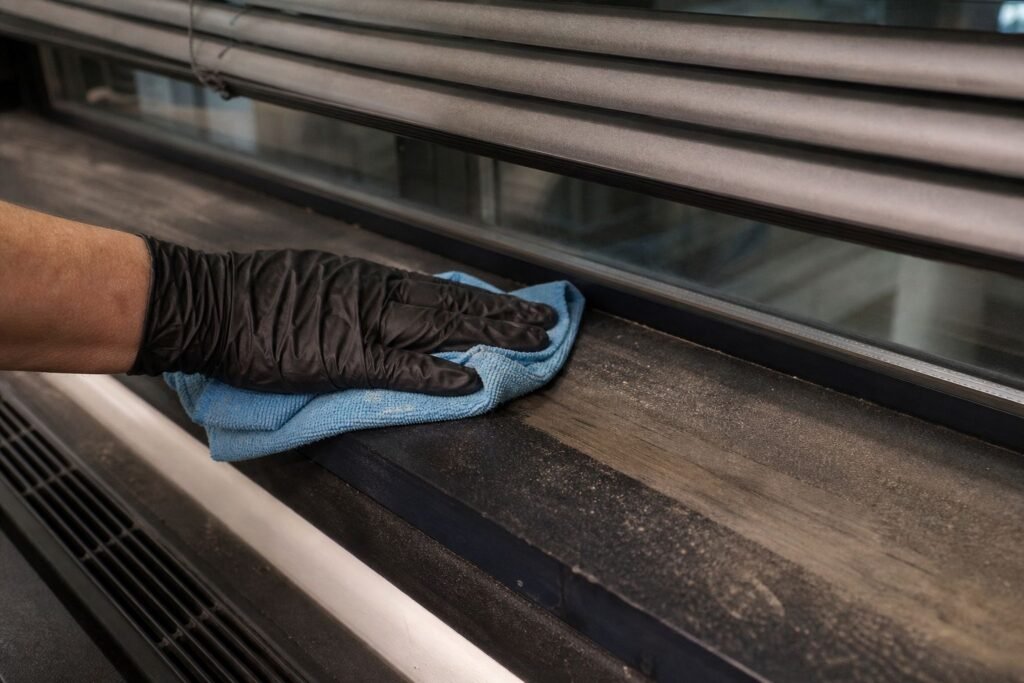Hand wiping dust from an office window sill