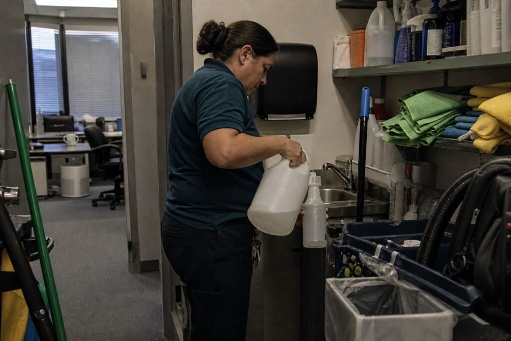 Cleaner refilling a spray bottle in a janitor closet