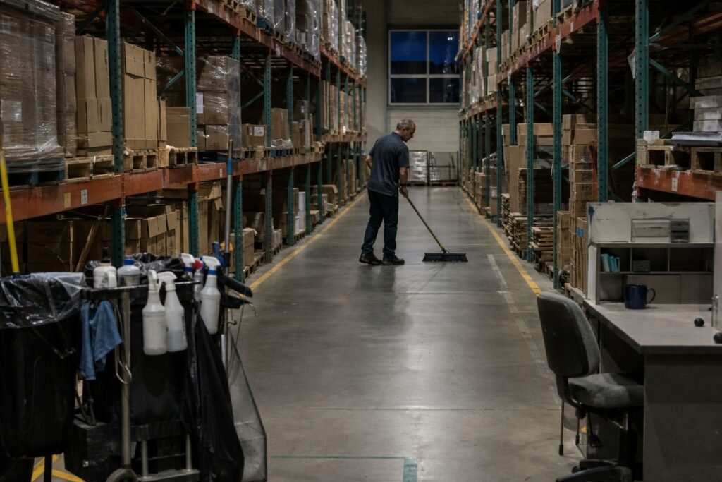 Cleaner sweeping a warehouse aisle