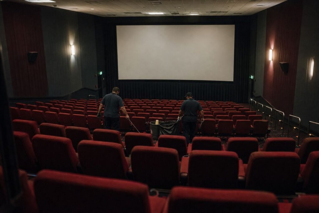 Cleaners clearing rows of seats in an empty movie theater