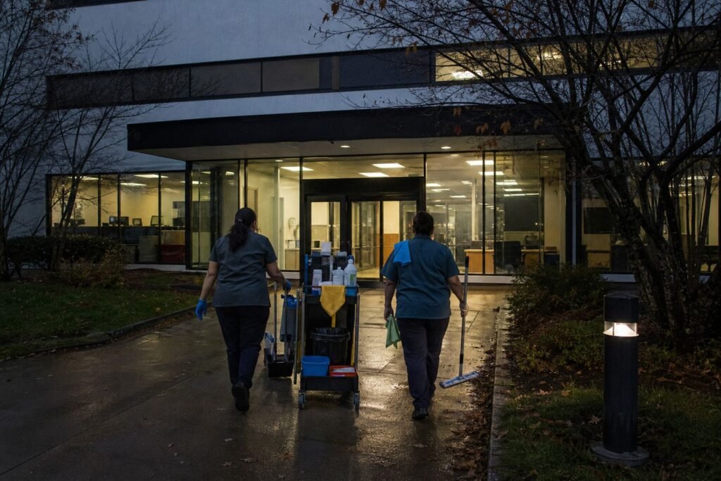 Two cleaners arriving at an office building at dusk