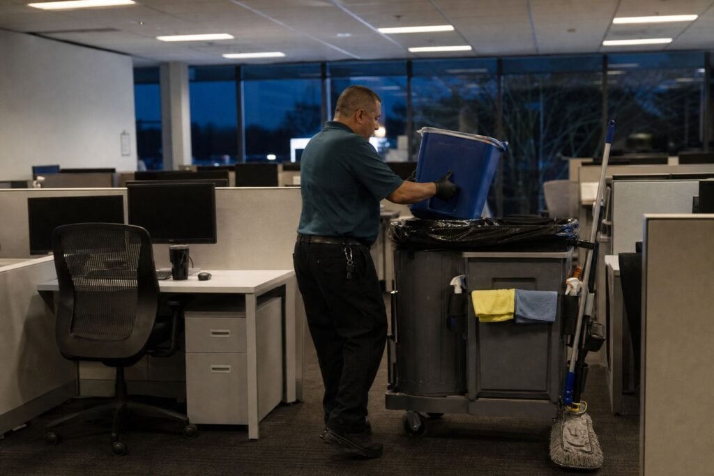 Cleaner collecting recycling from desks in an office