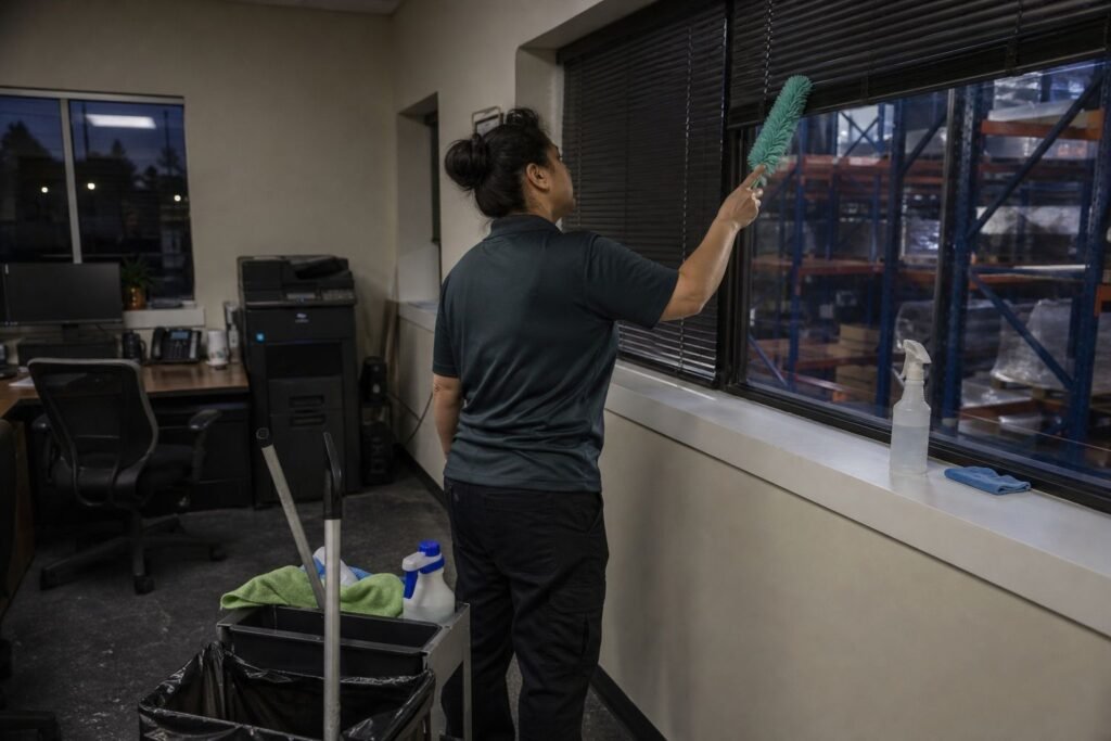 Cleaner dusting window blinds in a warehouse front office