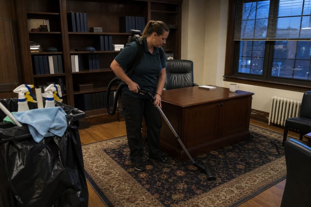 Cleaner vacuuming a small private office